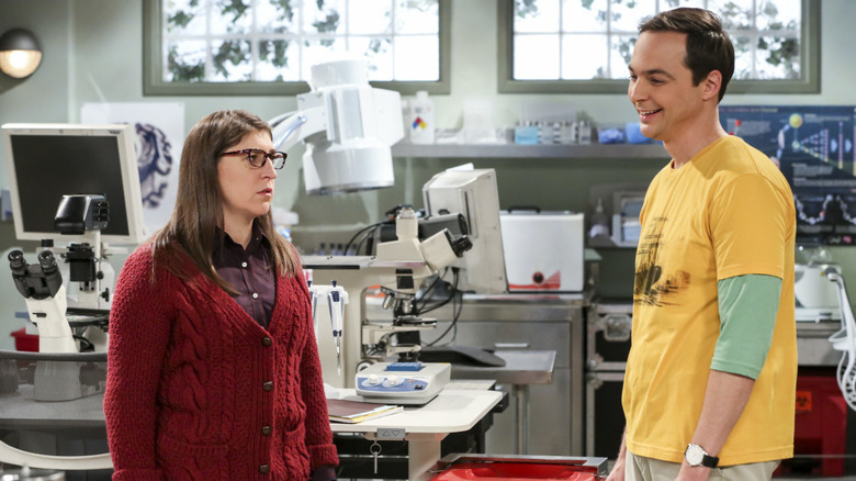 Amy looking aggrieved in her lab while Sheldon laughs at something on The Big Bang Theory