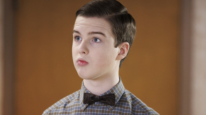 Young Sheldon Cooper posing in front of flowers