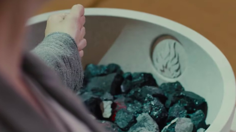 A hand in a fist over one of the Choosing Ceremony bowls
