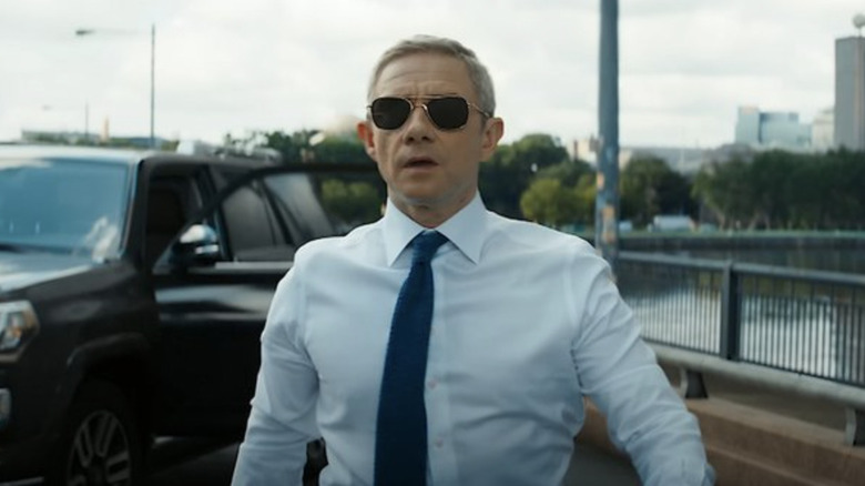 Everett Ross wears suit on a bridge