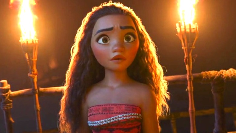 Moana standing by some torches in the dark