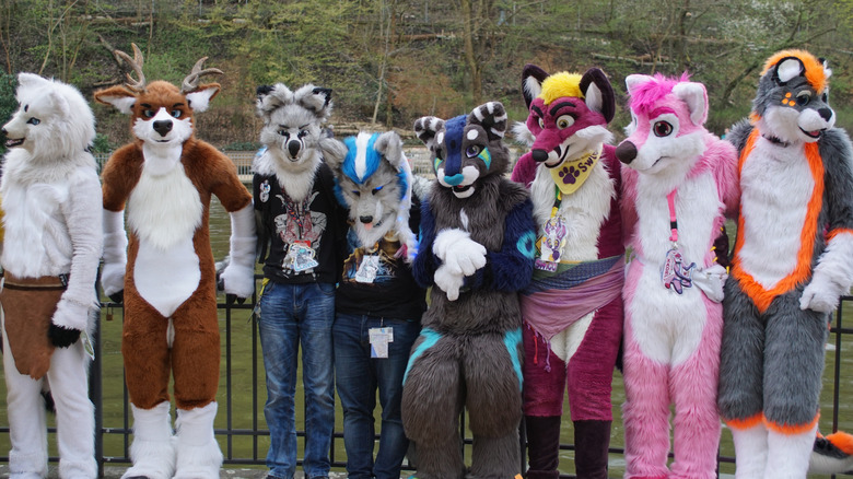 A group of fursuiters stand together by a railing