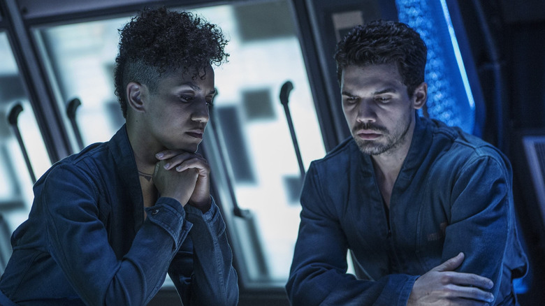 Naomi and Jim sitting at table seriously in 