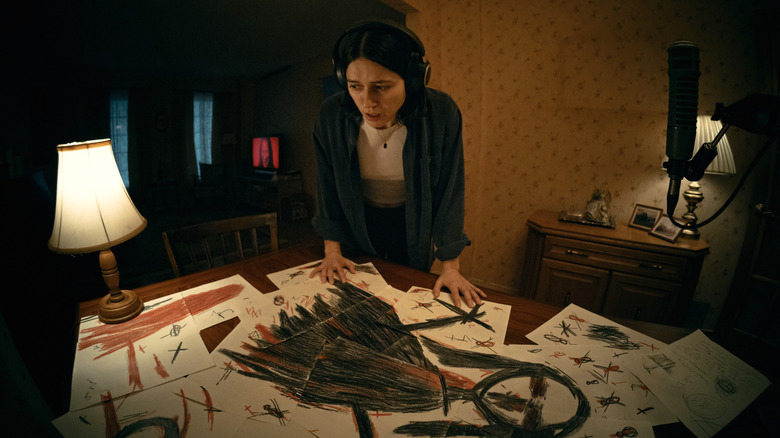 Evy looks at frightening drawings on her dining room table in "Undertone" (2026)