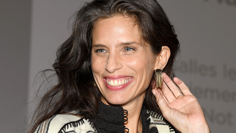 Maïwenn smiling with her hand behind her earring
