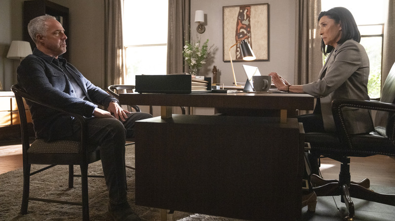 Titus Welliver and Mimi Rogers sitting in an office