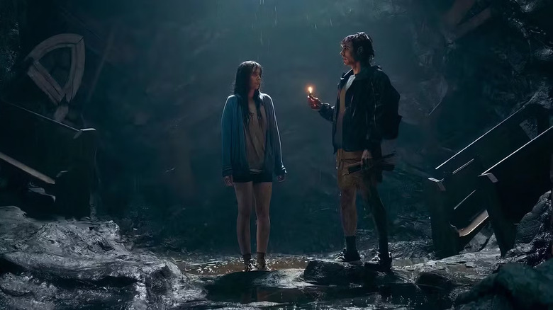 Tim holds a lighter with Millie in a cave in 