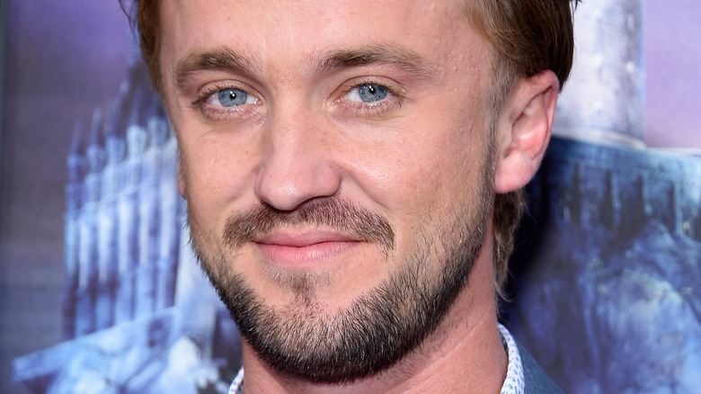 Tom Felton grinning at a press event