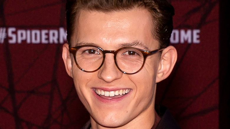 Tom Holland in glasses smiling at camera 