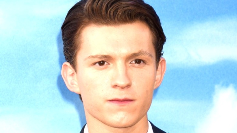 Tom Holland standing by blue background
