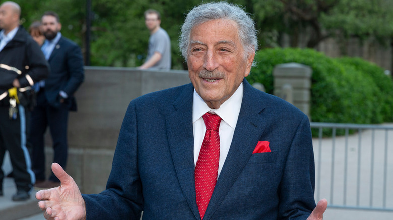 Tony Bennett smiling warmly in dark blue suit and red tie