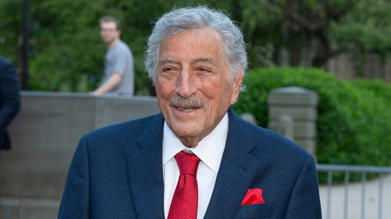 Tony Bennett smiling warmly in dark blue suit and red tie