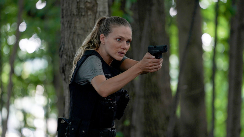 Tracy Spiridakos holding gun in forest