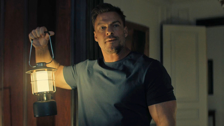 Jack Reacher holds up a lantern on "Reacher" (2022-present)