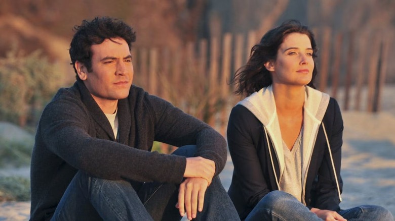 Ted and Robin sitting on a beach in "How I Met Your Mother."