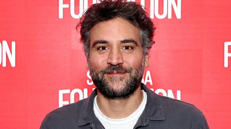 Josh Radnor standing in front of red background