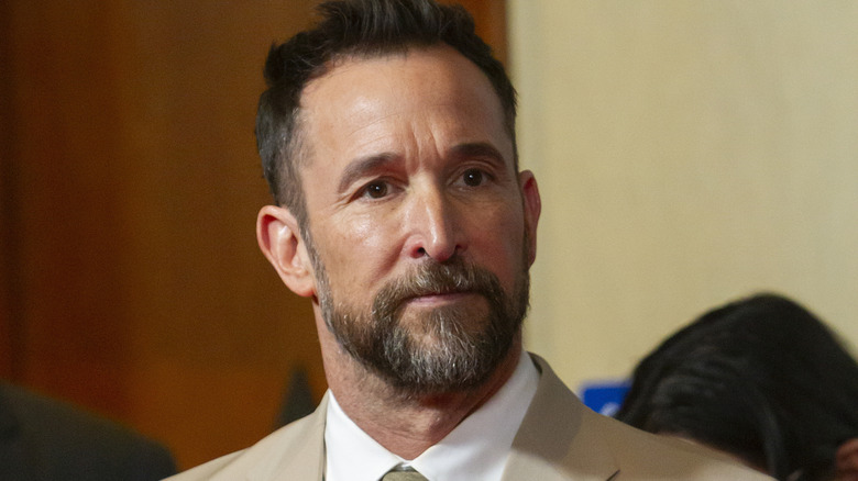 Noah Wyle wearing a suit and tie