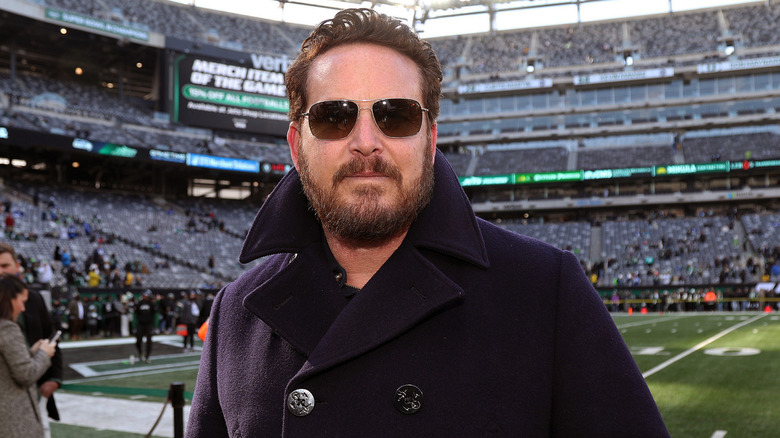 Cole Hauser in a coat at a football stadium