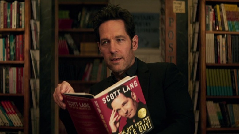 Scott Lang looking to his right while holding his own autobiography in Ant-Man and the Wasp: Quantumania (2023)