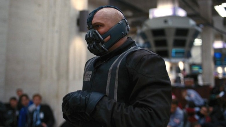 Bane standing in front of cowered hostages at the Gotham Stock Exchange in The Dark Knight Rises (2012)