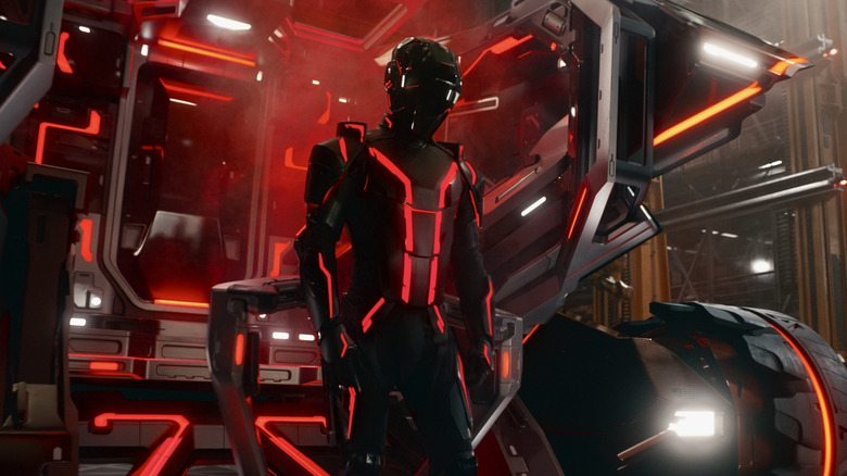 Ares wearing a light suit by his vehicle