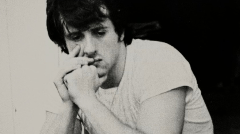 Younger Sylvester Stallone sitting thinking