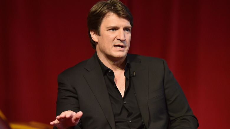 Nathan Fillion in front of red curtain
