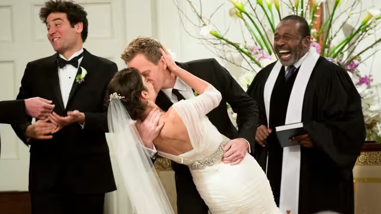 Ted laughs next to Barney and Robin at their wedding