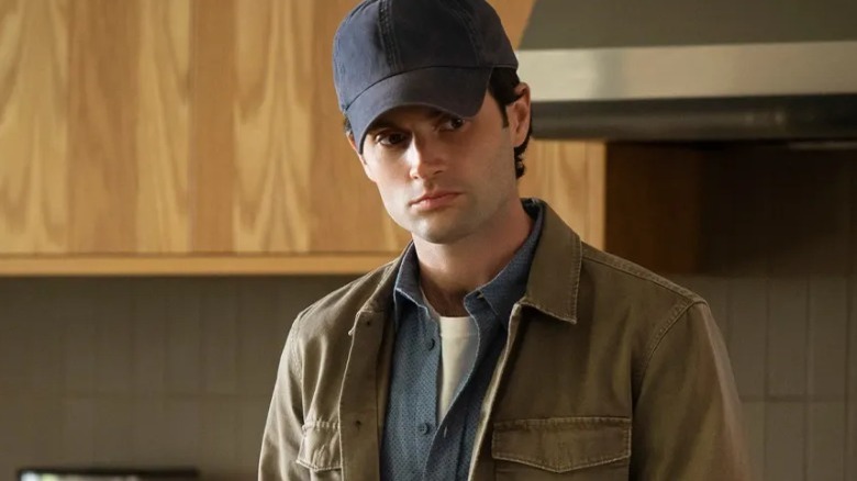 Joe Goldberg wearing a cap in kitchen
