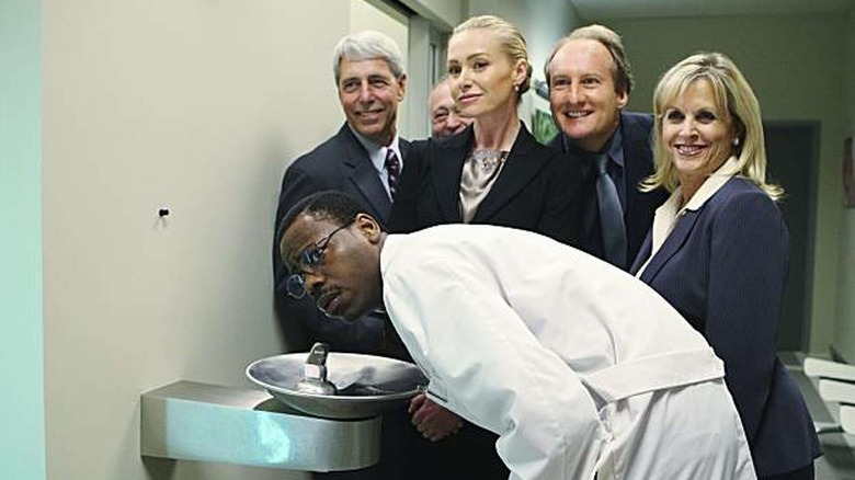 Veronica Palmer and the Veridian Dynamics executives stand behind Lem as he drinks from a water fountain in "Better Off Ted"