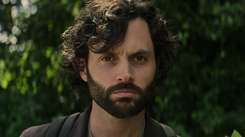 Joe with a beard standing near some trees in 