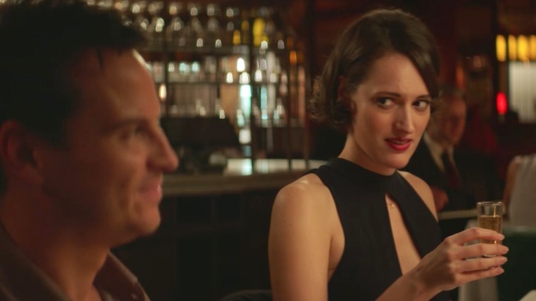 Fleabag sits at a bar and looks at the Priest with skepticism.