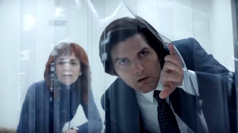 Mark pulls aside a clear plastic curtain and looks through.