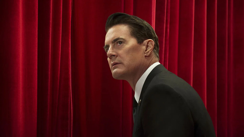 Agent Cooper sits in front of a red velvet curtain wearing a black suit in "Twin Peaks: The Return" (2017)