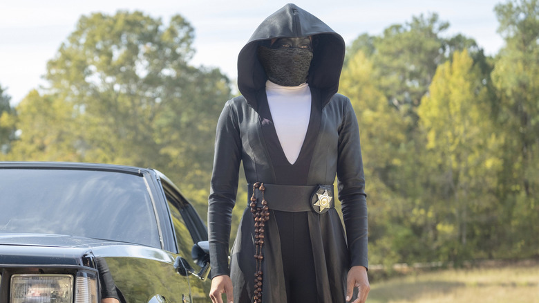Sister Night in uniform standing by her car in Watchmen