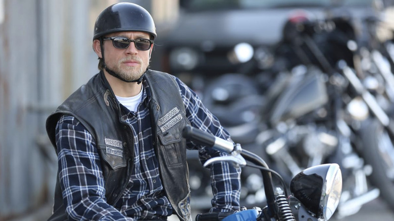 Jax Teller in helmet and sunglasses sitting on motorcycle