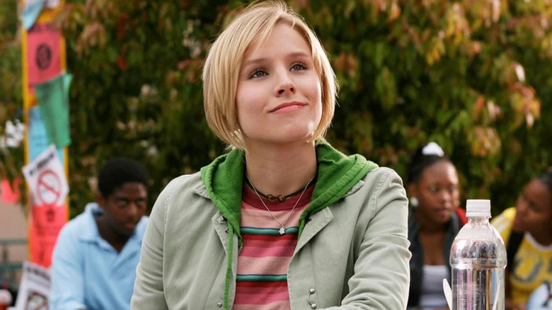 Veronica Mars smiling and sitting outdoors on "Veronica Mars" (2004-2007, 2019)
