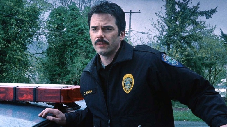 Charlie Swan leaning on police car