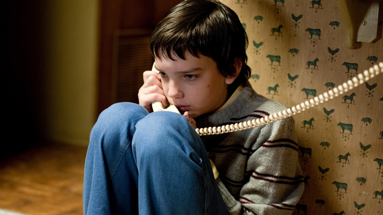 Owen sitting on the floor using the phone in Let Me In (2010)