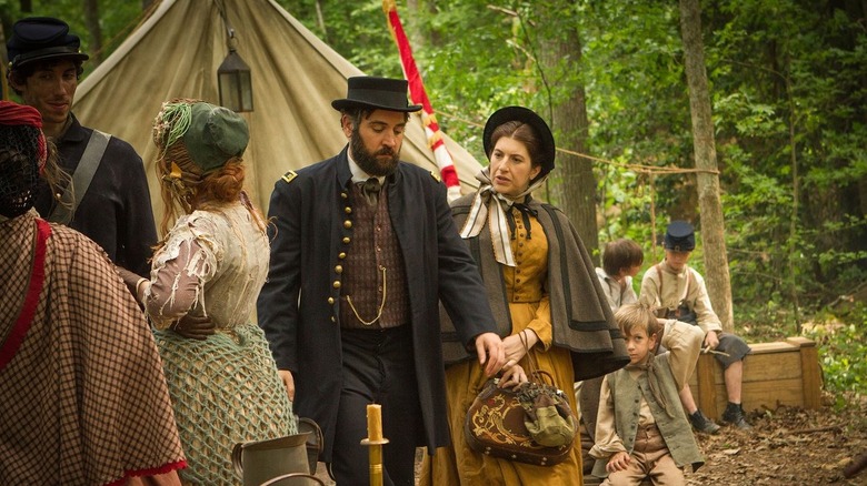 A nurse helps a man through an encampment