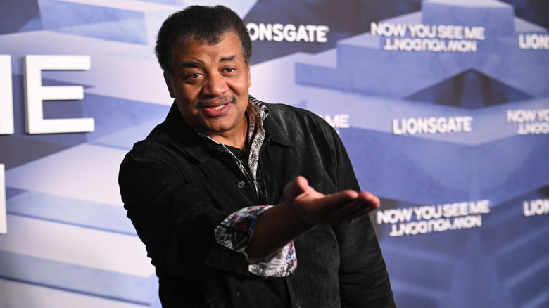Neil deGrasse Tyson posing with his hand up