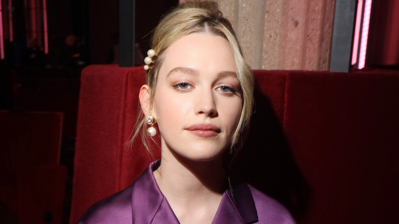 Victoria Pedretti sitting down and wearing a purple top