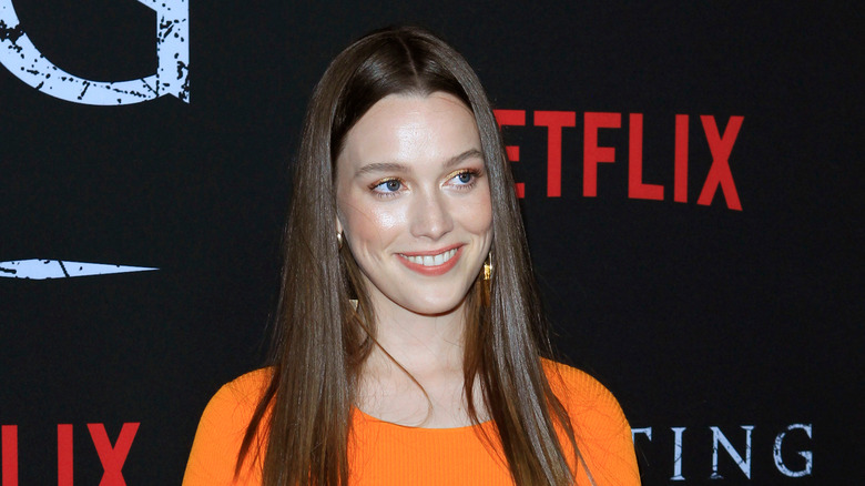 Victoria Pedretti wearing an orange top and smiling