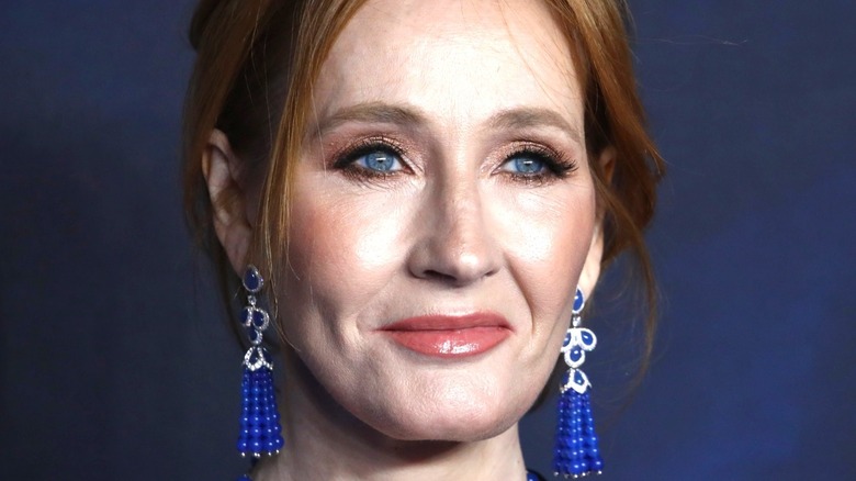 J.K. Rowling smiling in front of a blue backdrop