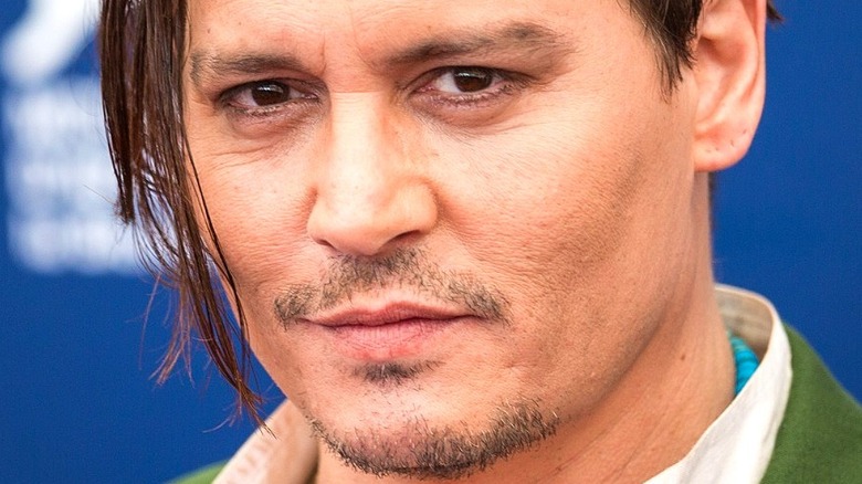 Johnny Depp stands in front of a blue background