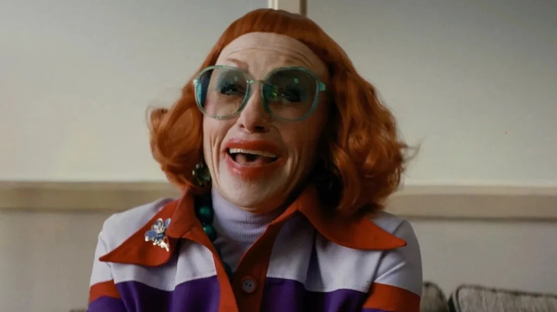 Gladys in her full wig and makeup and glasses in Marcus' office in Weapons