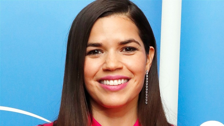 America Ferrera smiles in front of blue backdrop