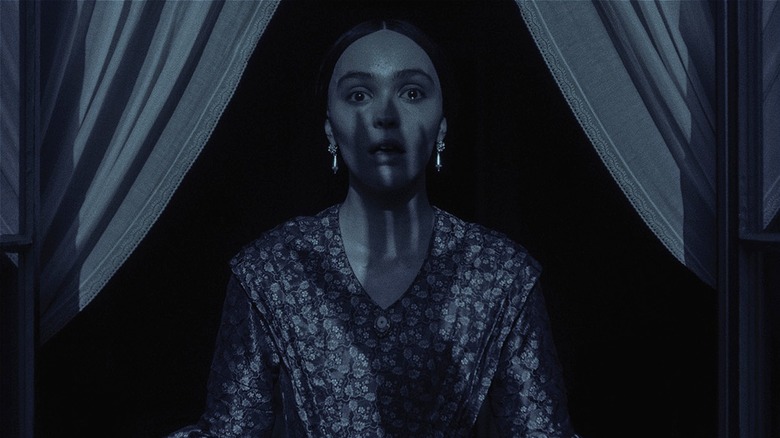 Ellen crying in fear as a shadow of Orlok's hand appears on her face in Nosferatu (2025)