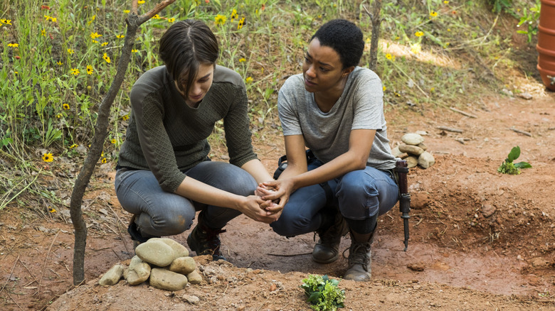 Maggie and Sasha kneeling beside Glenn's grave in "The Walking Dead"