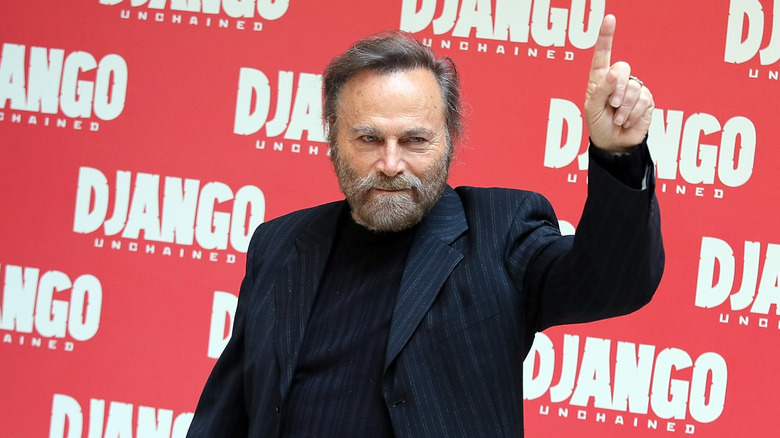 Franco Nero pointing up in front of a Django Unchained display